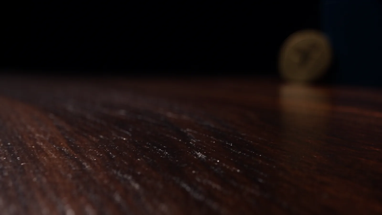 A brushed-gold Velu medallion and midnight-blue stationery on polished walnut.